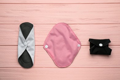 Photo of Many reusable cloth menstrual pads on pink wooden table, flat lay