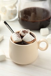 Photo of Cup of aromatic hot chocolate with marshmallows and cocoa powder on white wooden table