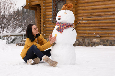 Young woman near funny snowman outdoors. Winter vacation