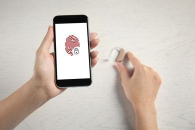 Set up hearing aid with smartphone app, fingerprint sensor on screen, top view. Digital identity