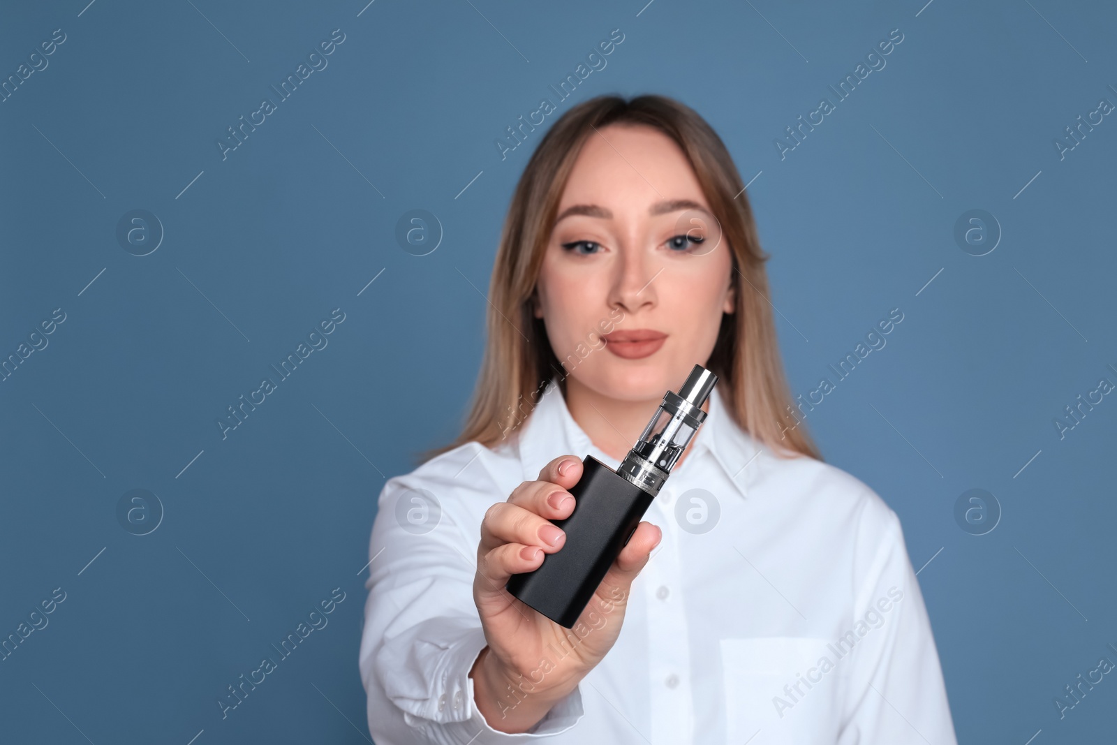 Photo of Young woman holding electronic cigarette against light blue background, focus on hand. Space for text