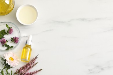 Flat lay composition with bottle of cosmetic oil on white marble table, space for text