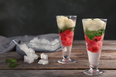 Photo of Glasses with tasty melon and watermelon ball drinks on wooden table