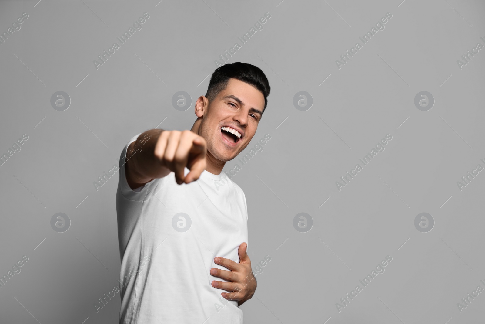 Photo of Handsome man laughing on grey background. Funny joke