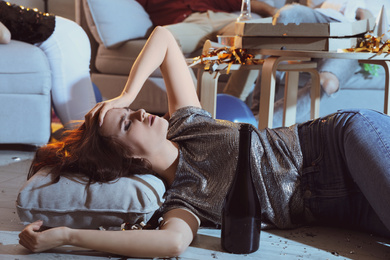 Young woman suffering from hangover in room after party