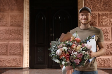 Happy delivery man with beautiful flower bouquet outdoors