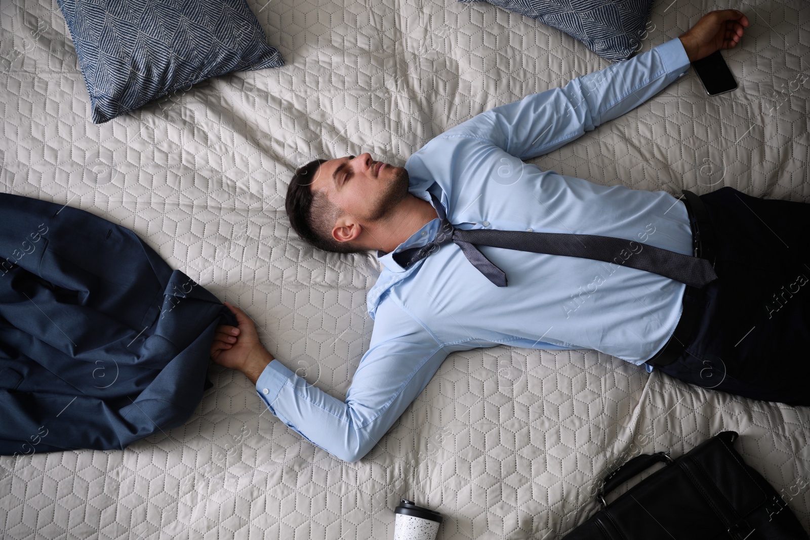 Photo of Exhausted businessman in office wear sleeping on bed at home after work, top view