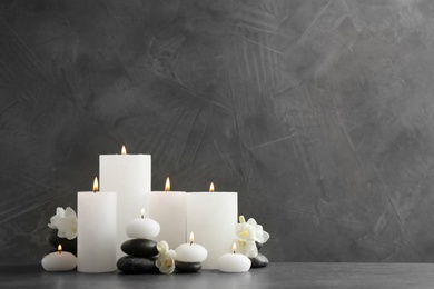 Photo of Beautiful composition with lit candles and flowers on table. Space for text