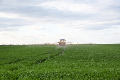 Photo of Tractor spraying pesticide in field on sunny day. Agricultural industry