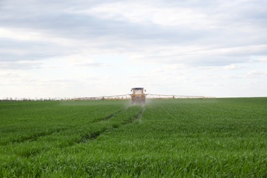 Tractor spraying pesticide in field on sunny day. Agricultural industry