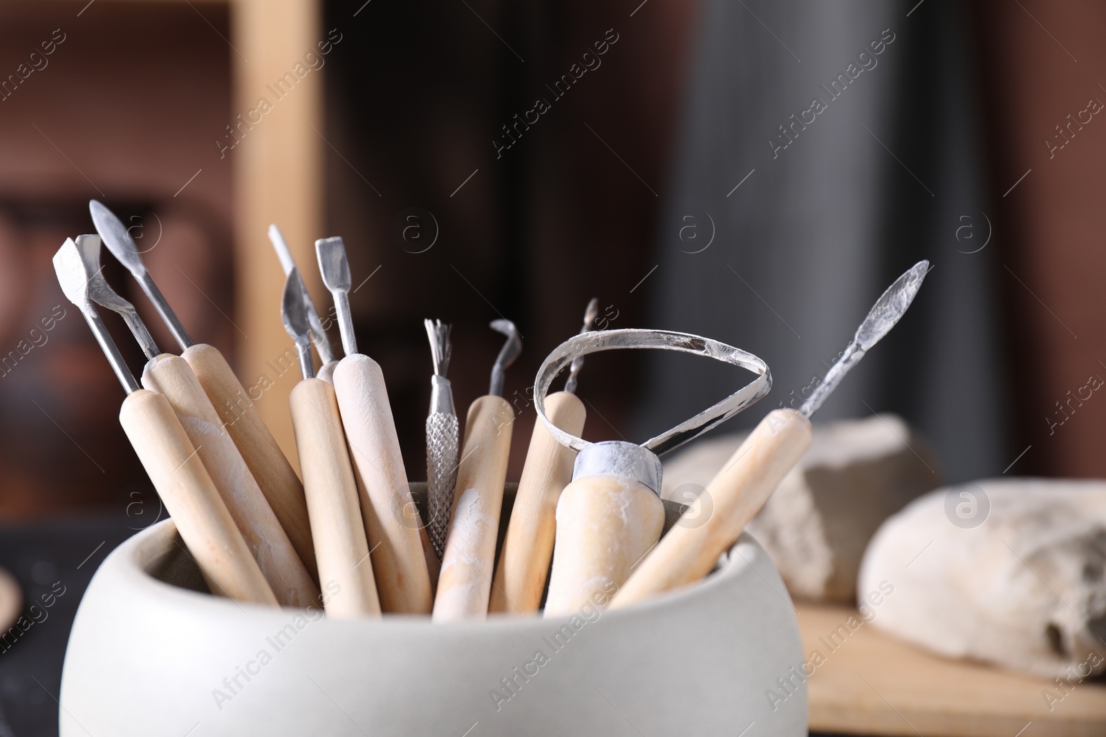 Photo of Set of different clay crafting tools on table in workshop, closeup