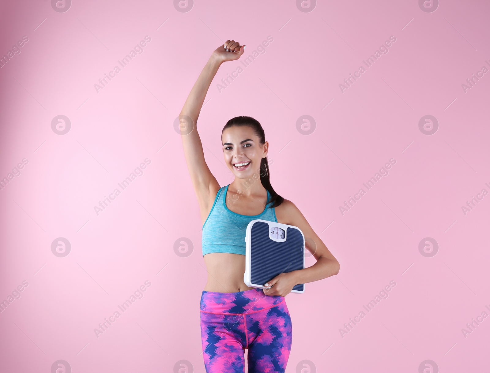 Photo of Happy young woman with scales on color background. Weight loss motivation