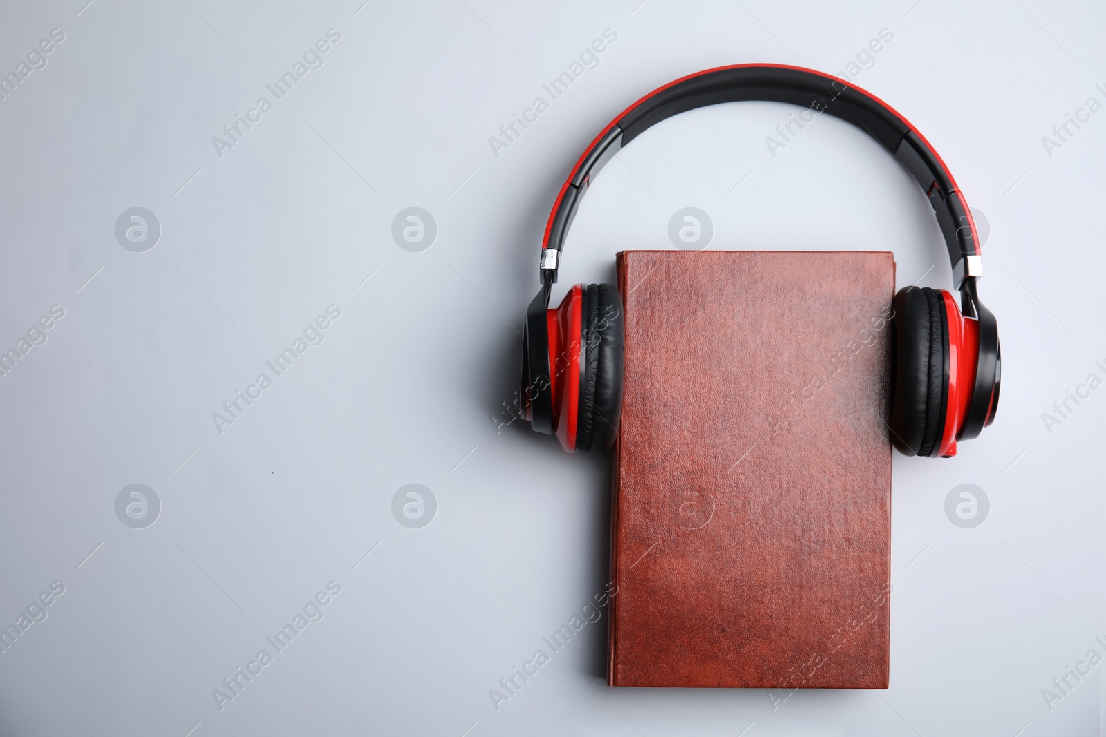 Photo of Book and modern headphones on grey background, top view. Space for text