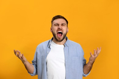 Photo of Angry young man on yellow background. Hate concept