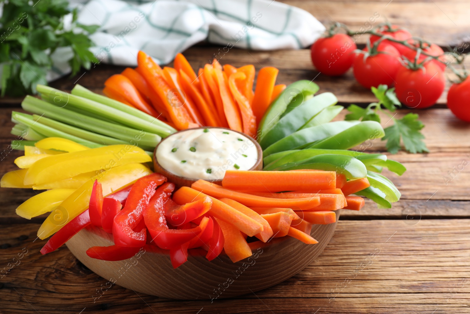 Photo of Different vegetables cut in sticks and dip sauce on wooden table, closeup