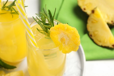 Glasses of tasty pineapple cocktail with rosemary on table, closeup