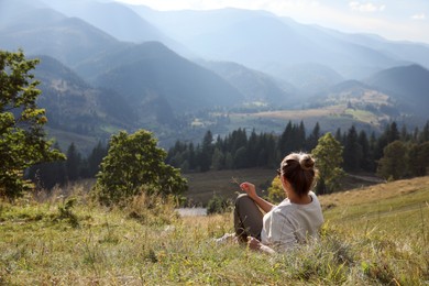 Photo of Woman enjoying beautiful mountain landscape, back view. Space for text