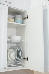 Clean plates and bowls on shelves in cabinet indoors