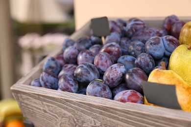Photo of Fresh ripe fruits in wooden crate at market, closeup. Space for text