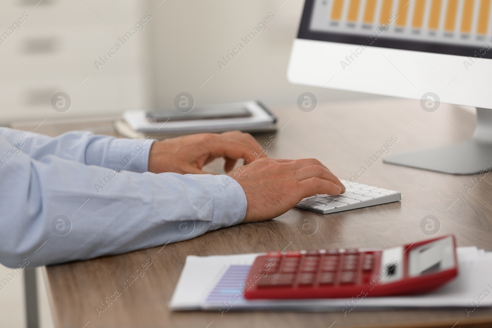Photo of Professional accountant working on computer at wooden desk in office, closeup