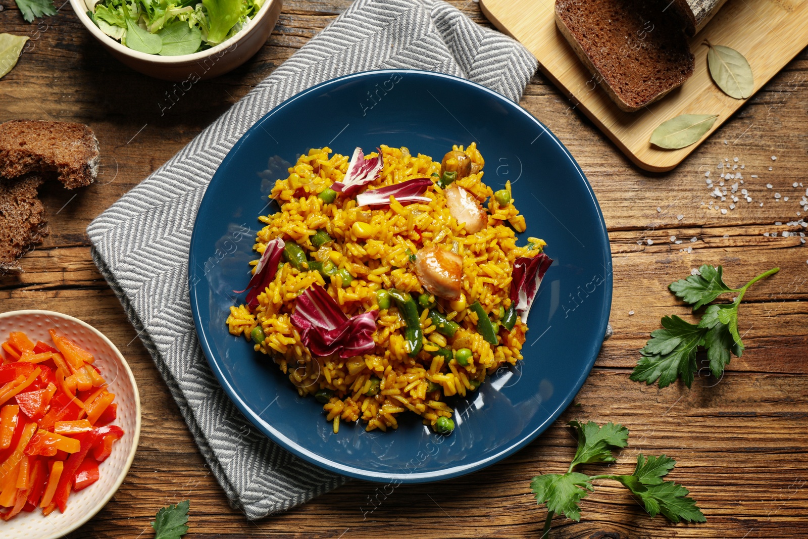 Photo of Delicious rice pilaf with chicken served on wooden table, flat lay