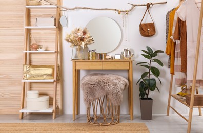 Stylish room interior with modern wooden dressing table near white wall