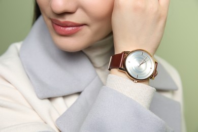 Photo of Woman with luxury wristwatch on green background, closeup