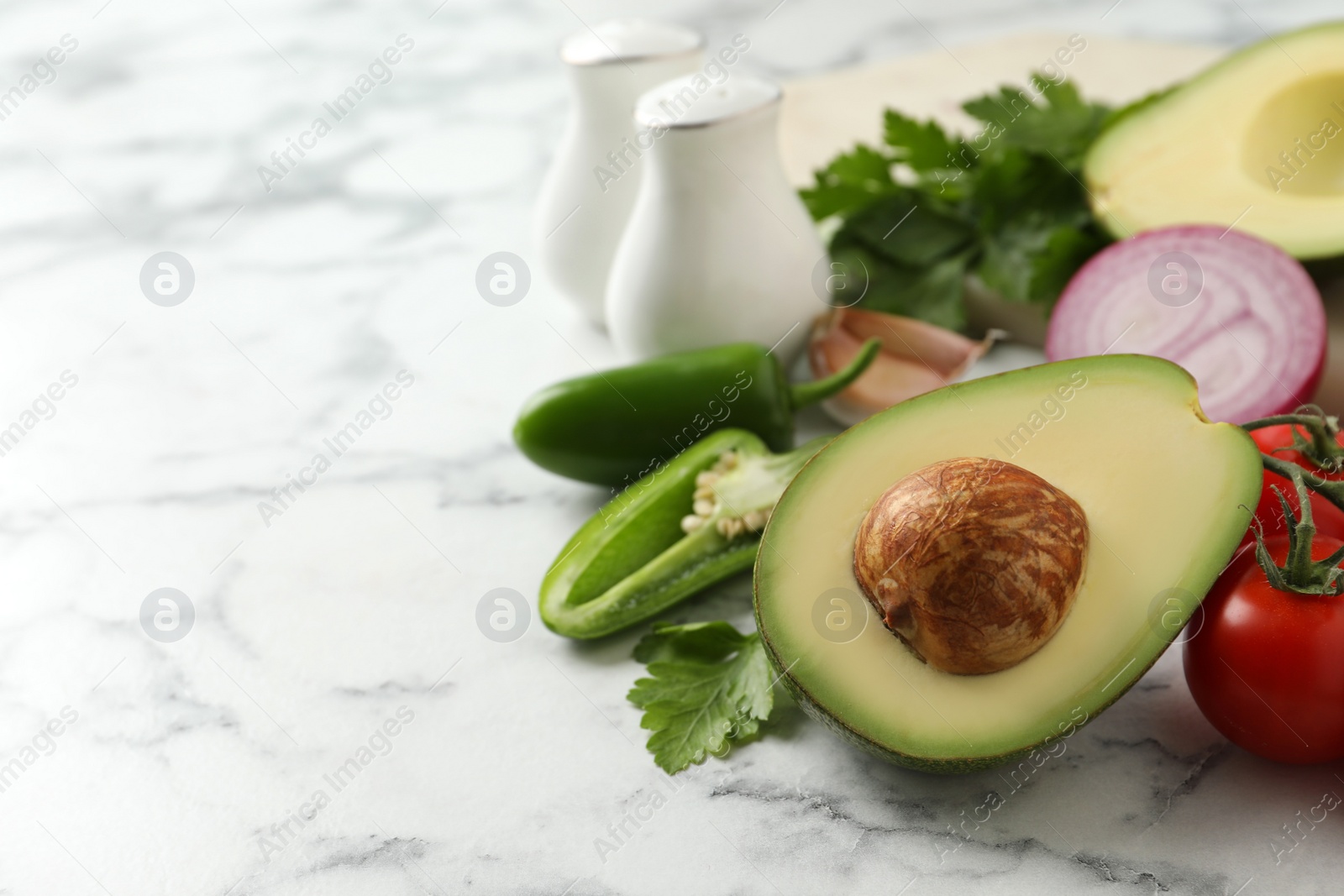 Photo of Fresh guacamole ingredients on white marble table. Space for text