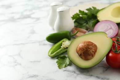 Fresh guacamole ingredients on white marble table. Space for text