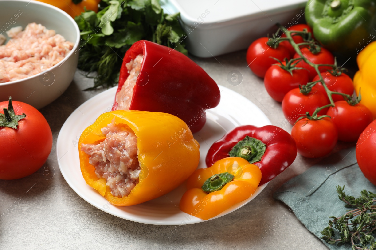 Photo of Raw stuffed peppers, ground meat and ingredients on grey table