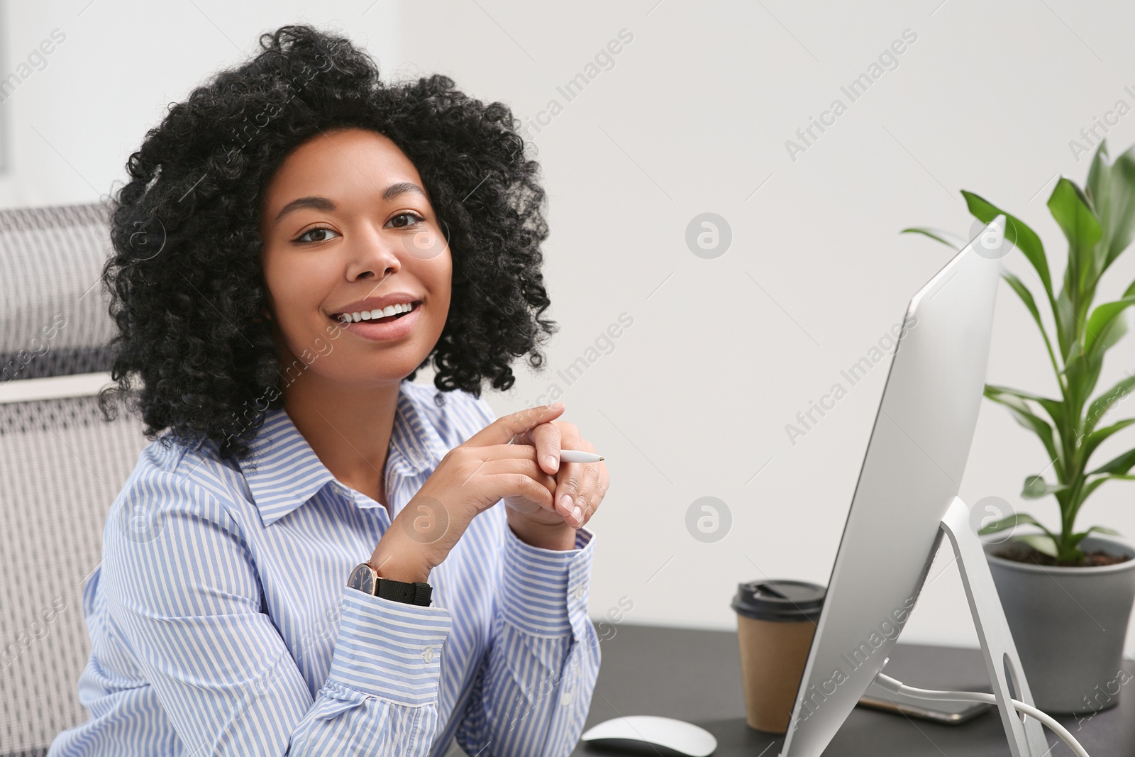 Photo of Young woman working on computer at table in office