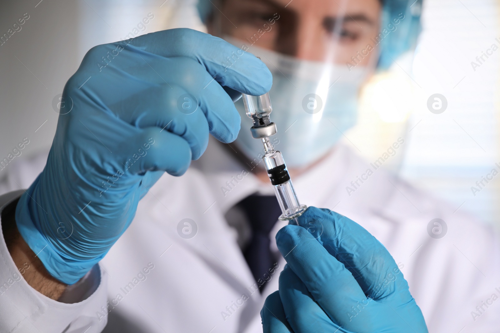 Photo of Doctor filling syringe with vaccine against Covid-19 in laboratory, focus on hands