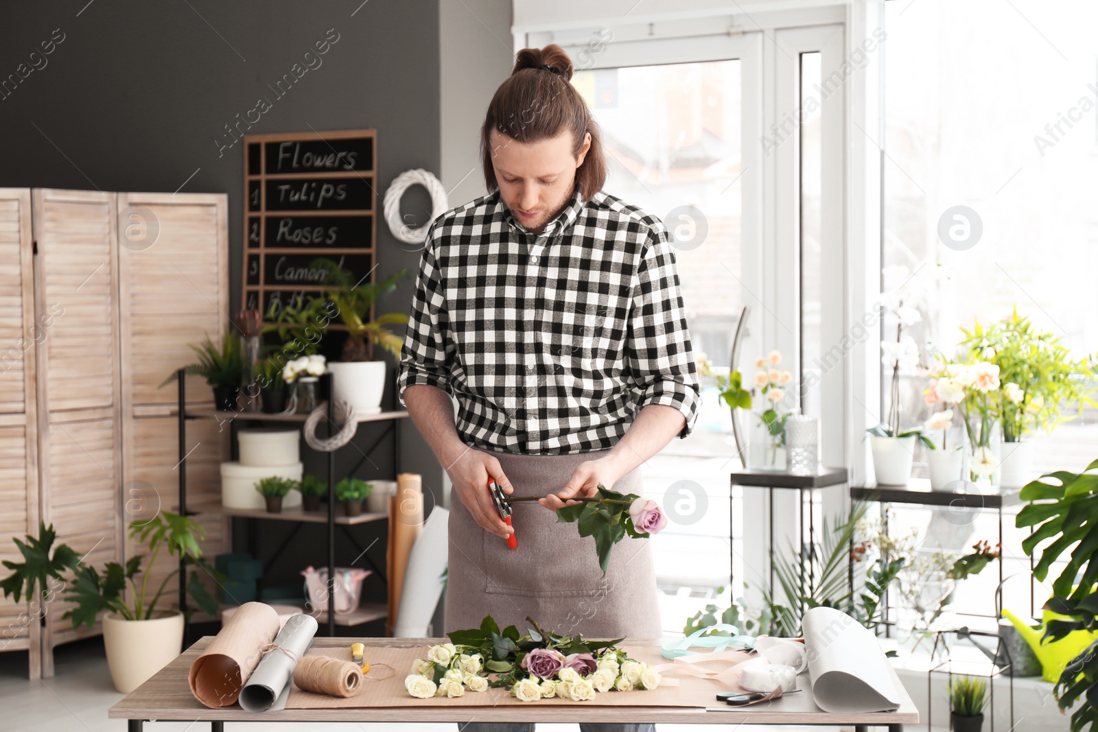 Photo of Male florist pruning rose for bouquet at workplace