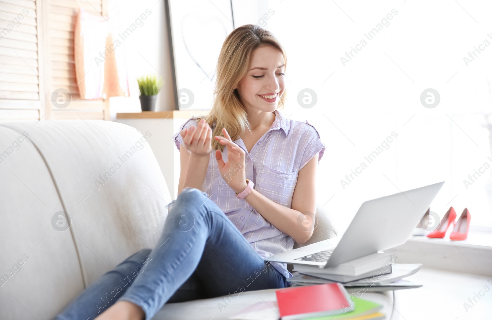 Photo of Young blogger with laptop sitting on sofa at home