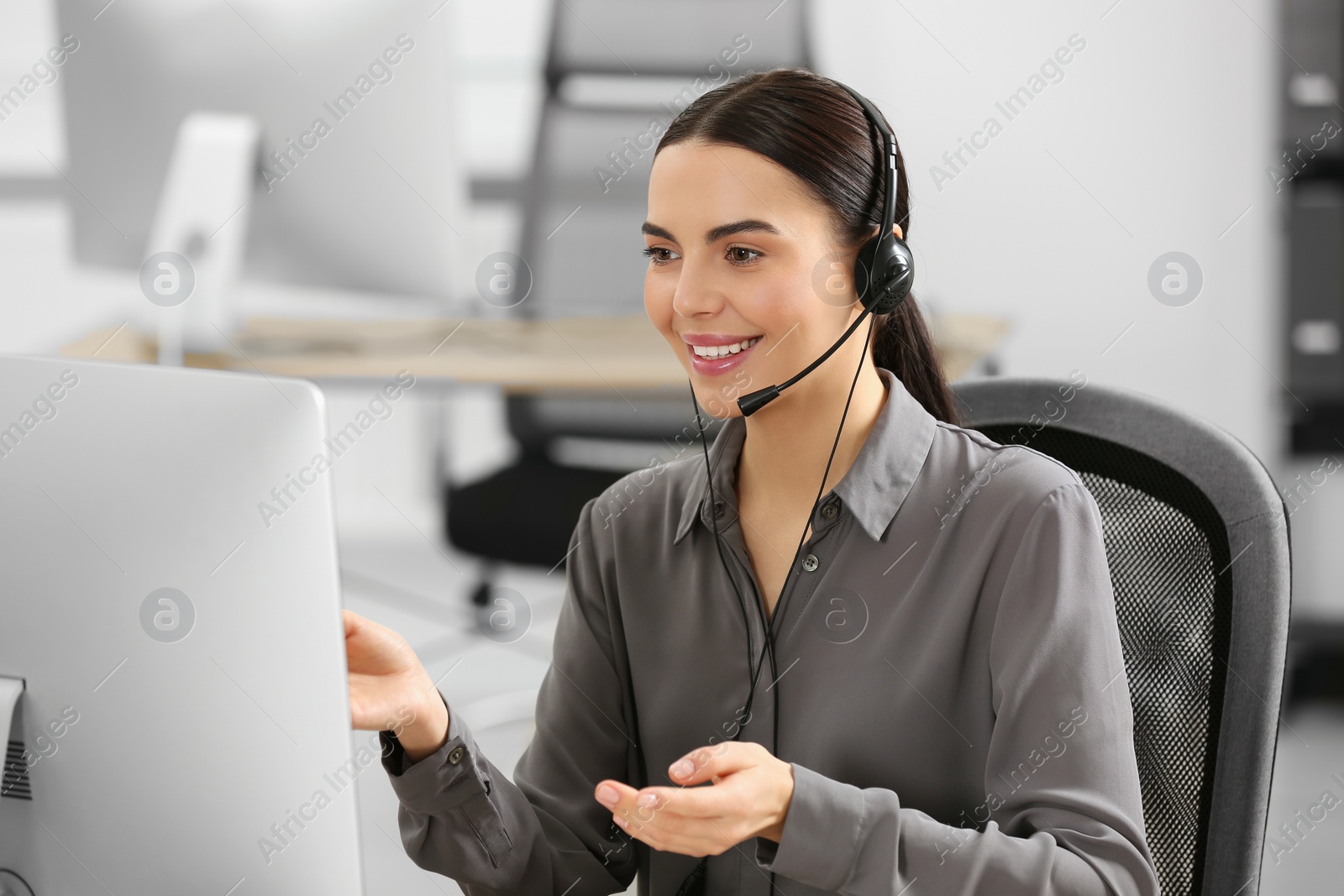 Photo of Hotline operator with headset working on computer in office