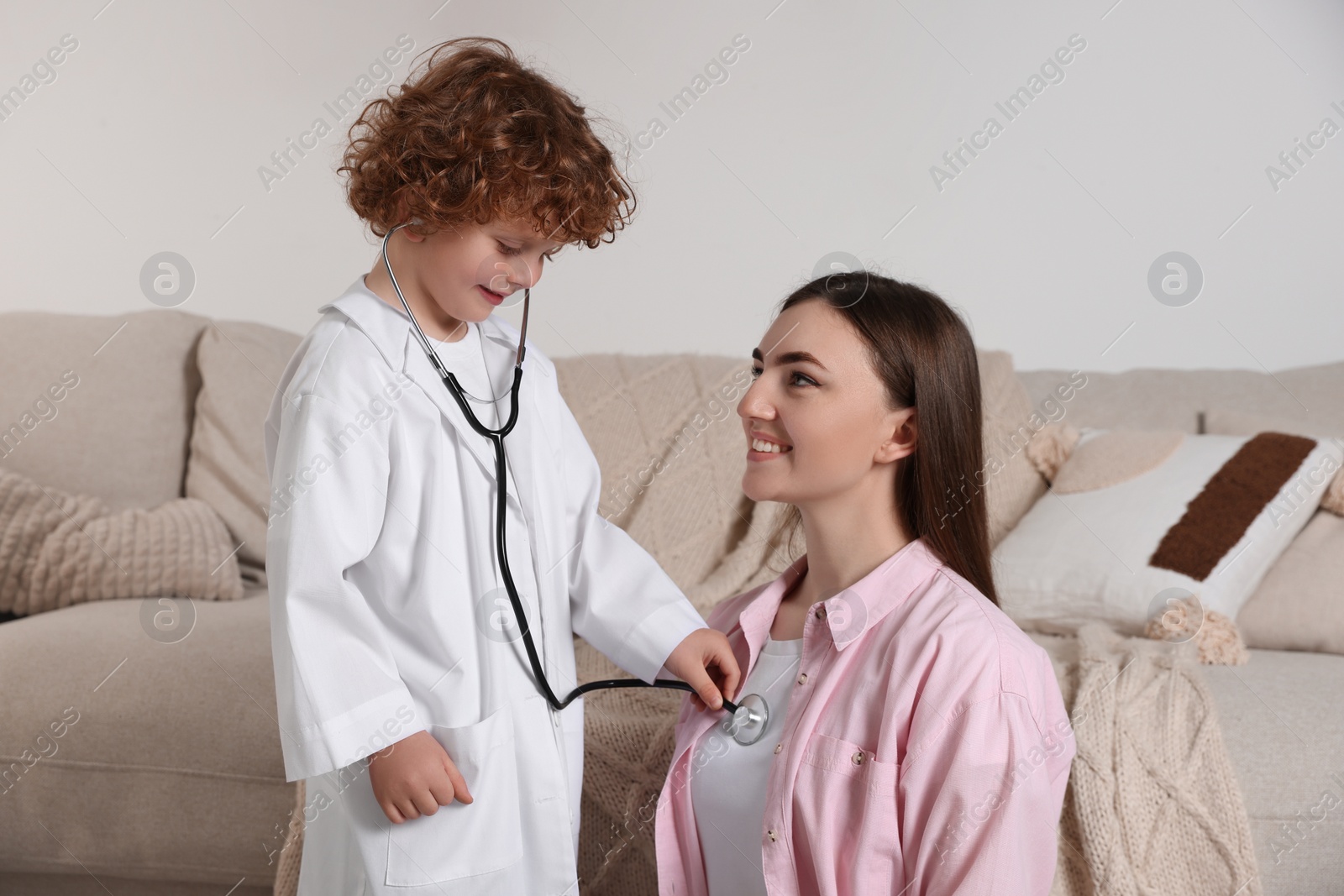 Photo of Little boy playing doctor with his mother at home