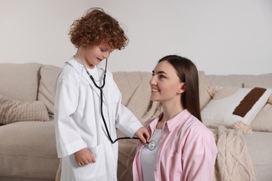 Little boy playing doctor with his mother at home