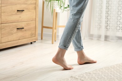 Photo of Woman stepping barefoot in room at home, closeup. Floor heating