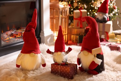 Cute Christmas gnomes and gift in room with festive decorations