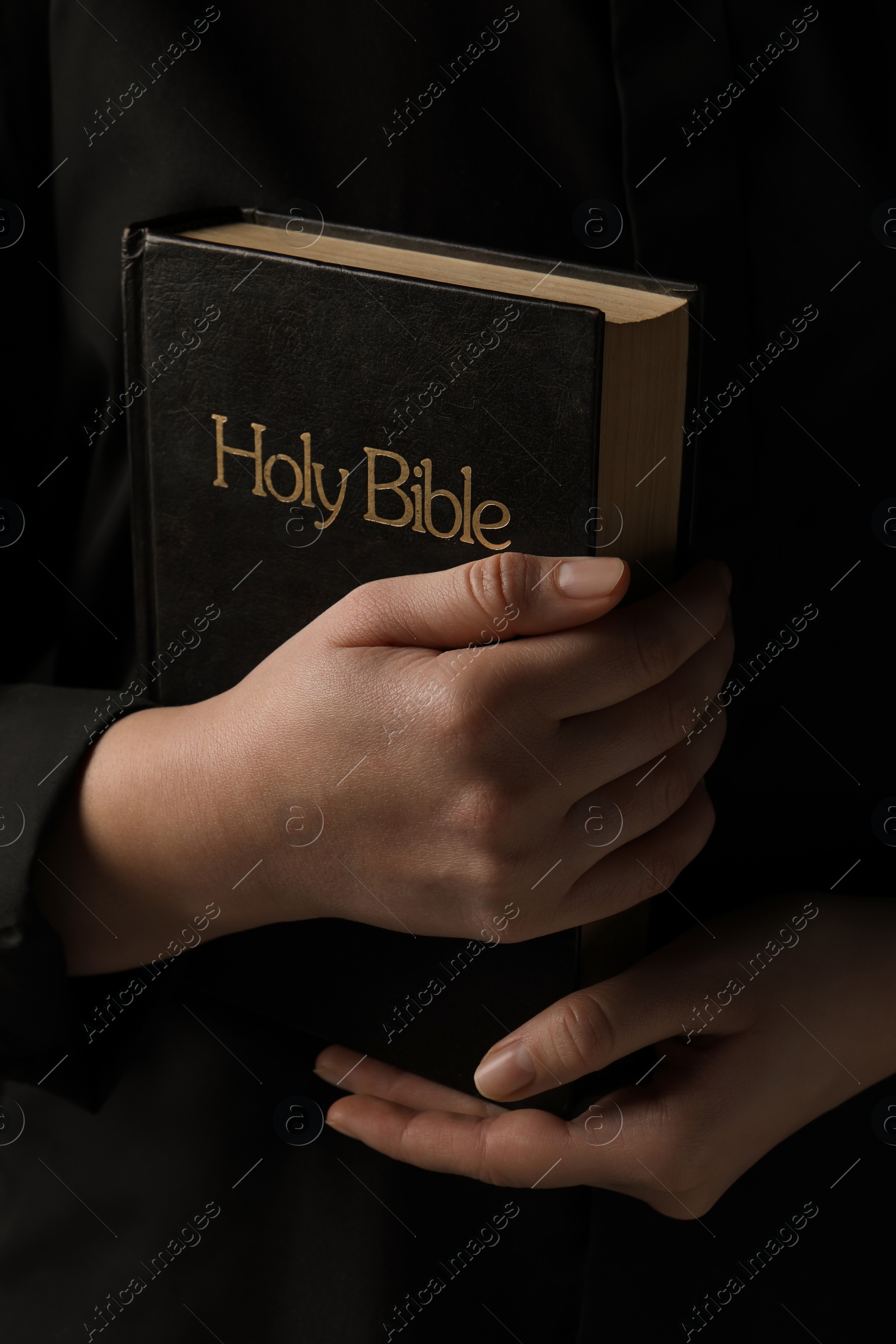 Photo of Woman with holy Bible on black background, closeup