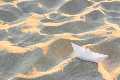 Photo of Beautiful white paper boat on sand outdoors, space for text