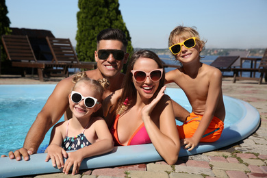 Happy family in outdoor swimming pool on sunny summer day
