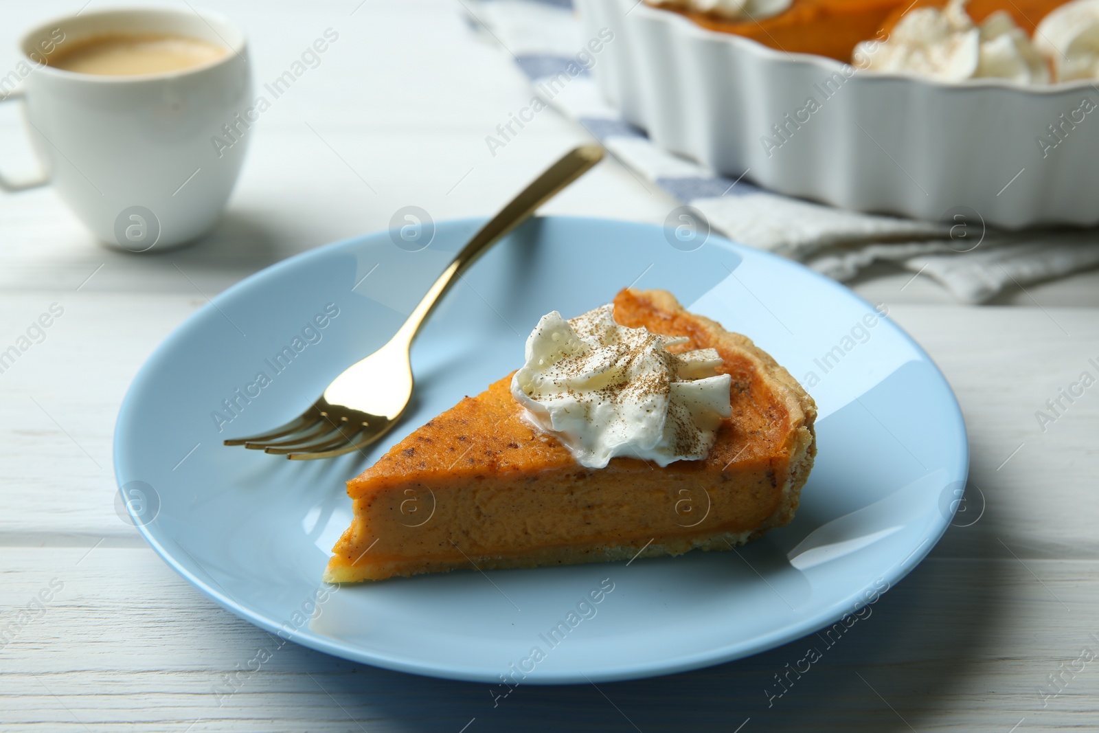 Photo of Piece of delicious pumpkin pie with whipped cream and fork on white wooden table, closeup