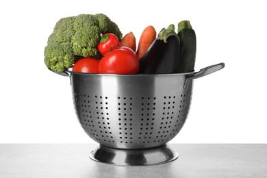 Photo of Different fresh vegetables in colander on table against white background