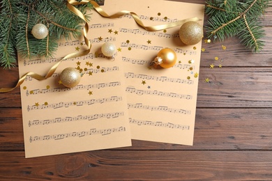 Flat lay composition with Christmas decorations and music sheets on wooden background