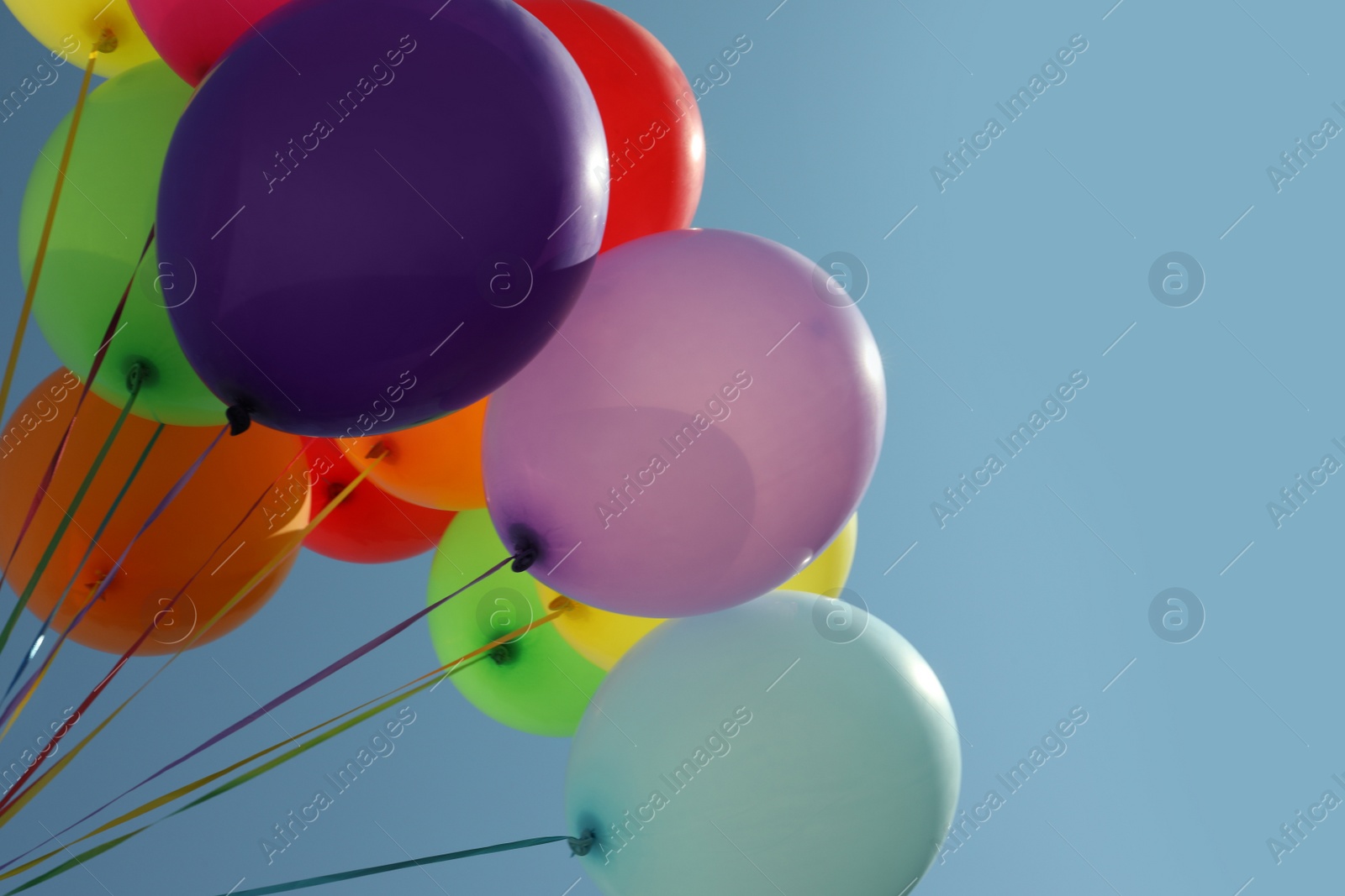 Photo of Bunch of colorful balloons against blue sky, low angle view