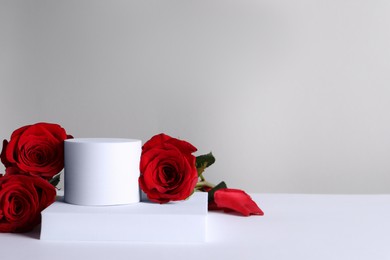 Photo of Stylish presentation for product. Beautiful red roses and geometric figures on light background, space for text