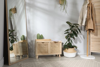 Stylish hallway room interior with wooden commode, coat rack and large mirror