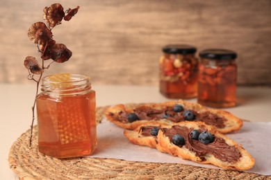 Composition with jar of honey and croissant on beige table