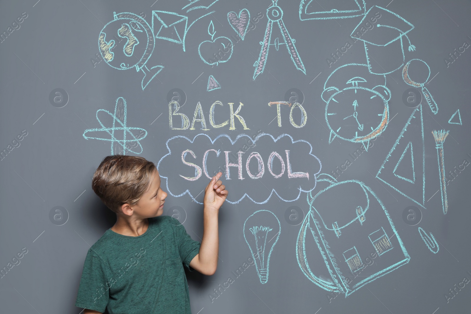 Photo of Little child near drawings and text BACK TO SCHOOL on grey background